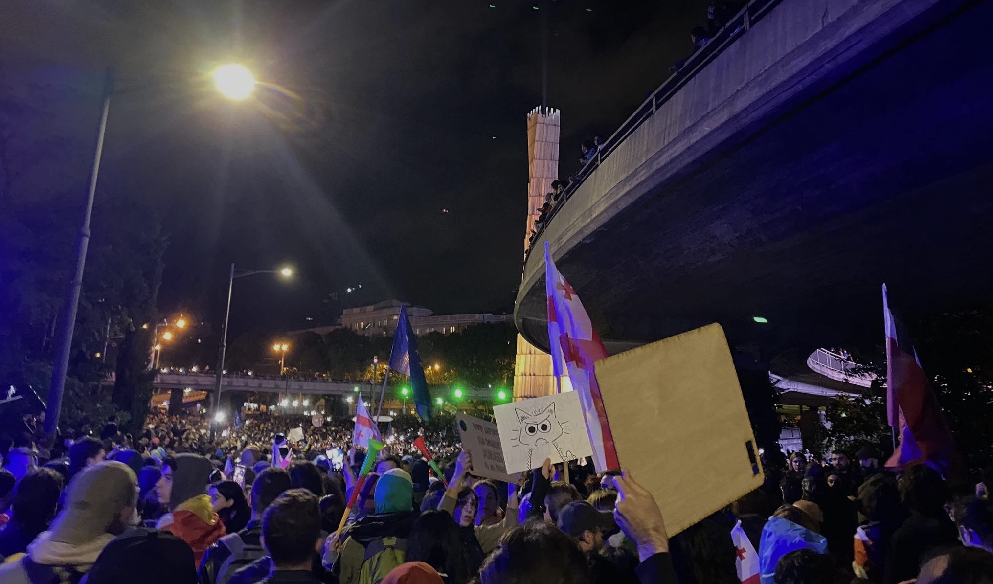 Menschen auf Demonstrationen abends in Tiflis,Georgien protestieren und halten Schilder und georgische und EU-Flaggen hoch